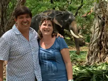 Individuelle Indienreise-Gäste(Georg & Moni) stehen vor dem Elefanten und sind herum die Bäume.